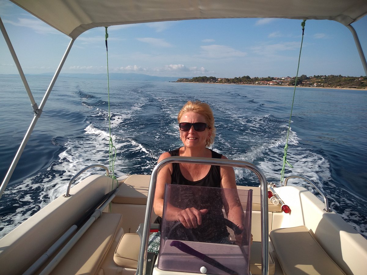 A guest smiling while steering a boat off Skala