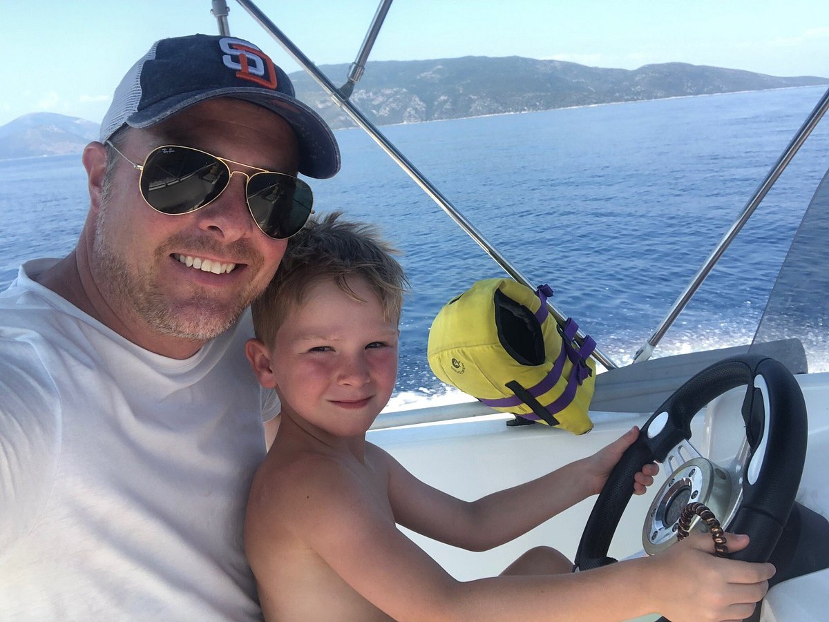 A young guest steering a boat with adult supervision